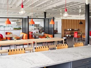 contemporary office kitchen, dining space with bar stools, large communal table, booths with privacy walls, designed for collaborative meals